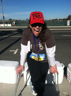 Aurora giving a big open mouth smile while leaning on her crutches after the Surf City half marathon 2012
