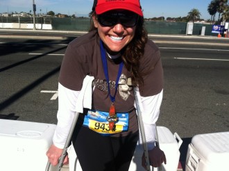 Aurora leaning on her crutches smiling at Surf City half marathon 2012