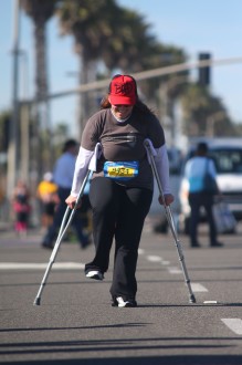 Aurora looks down while moving on crutches at the Surf City Half Marathon 2012