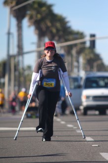 Aurora De Lucia with a large smile after finally (after over 5 hours) she hobbles in on her crutches to the finish of the Surf City half marathon 2012 (complete with sag wagon behind her)