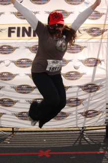 Aurora jumping (with a lot of hair flying in her face) in the finisher area of the North Carolina half marathon 2012