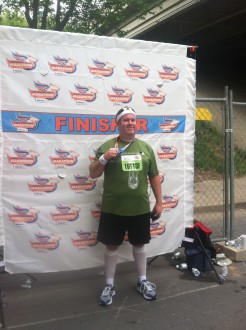 Randy posing in front of the finisher's backdrop at the Kentucky Derby miniMarathon