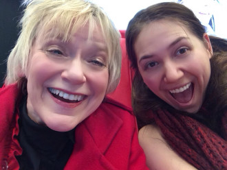 Selfie of Aurora and her high school theater teacher sitting on a red couch