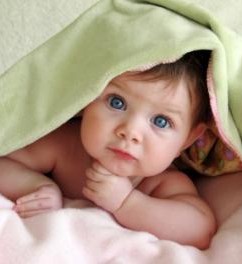 baby under a blanket giving an interested face with big eyes