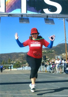 Aurora, wearing a lai, jumping at the finish line of the Malibu Half Marathon 2012