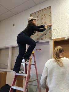 Aurora pulling tiles off the wall during a library renovation with the Do Good Bus
