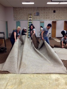Aurora and her group from the Do Good Bus pulling up carpet during a renovation