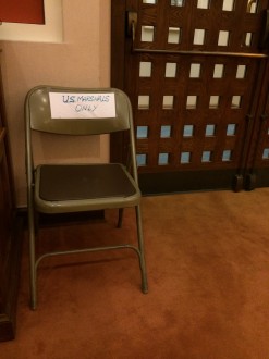 a handwritten sign that says US Marshals only taped to the back of a folding chair