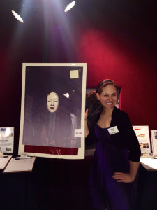 Aurora posing with silent auction materials at APLA stage event