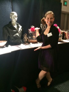 Aurora posing with some silent auction materials at APLA STAGE event