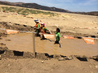 Aurora De Lucia being led through the mud while she wore a blindfold during the Irvine Lake Summer of Mud obstacle run 2014