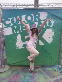 Aurora De Lucia stands on one foot on her toes, posing at the Color Me Rad sign