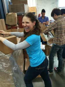 Aurora De Lucia giving a big smile while un-packaging boxes at Trash for Teaching