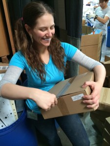 Aurora De Lucia smiling while opening a box at Trash for Teaching