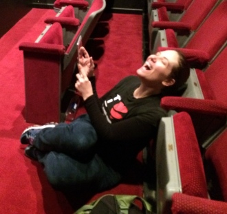 Aurora laughing by the seats in a theater