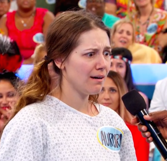 Aurora De Lucia giving crazy eyes, looking down, with a microphone pointed at her on Let's Make a Deal