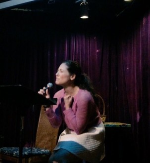 Aurora crouching down during open mic poetry