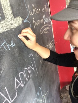 Aurora writing her favorite musical on the board at the Samuel French Bookshop