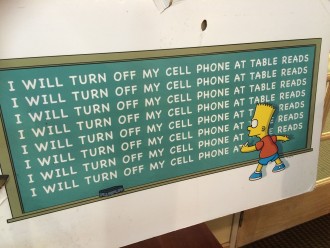 Bart Simpson writing "I will turn off my cell phone at the table read" on a chakboard on a sign on the Fox lot at The Simpsons table read
