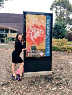 Aurora in front of the Up Here sign at La Jolla Playhouse