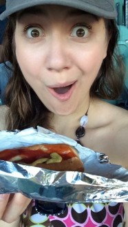 Aurora De Lucia with a surprised face while eating a hot dog